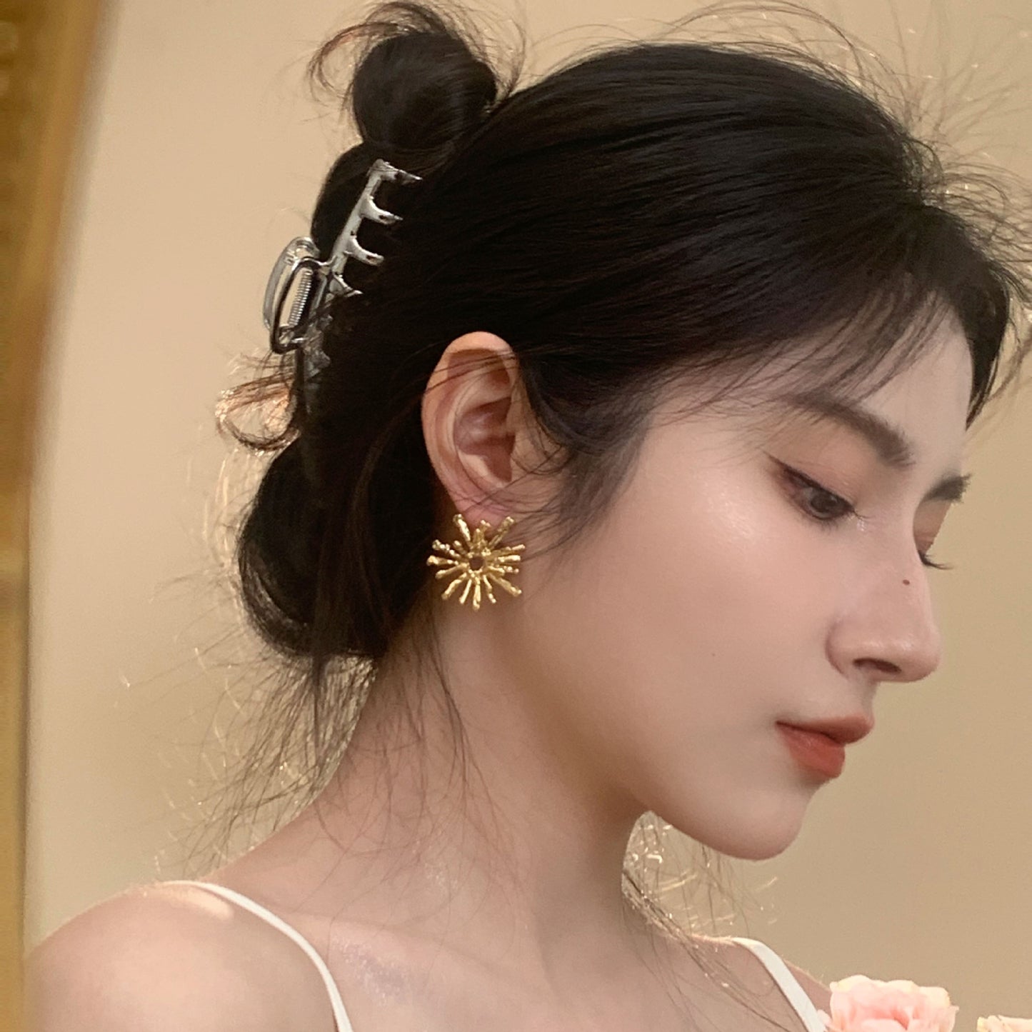 Close-up of a woman wearing gold earrings with a neutral background