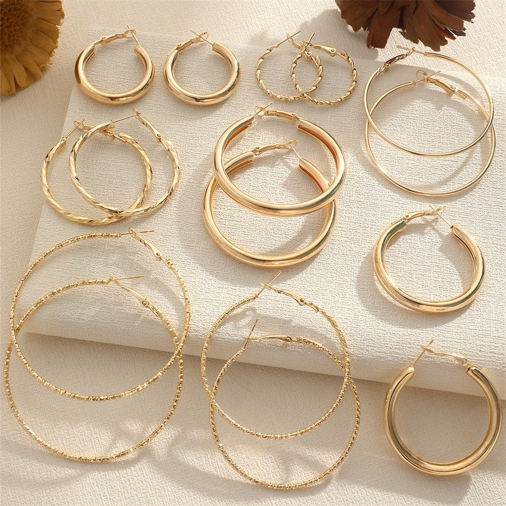 Collection of gold hoop earrings on a textured surface with a floral background.