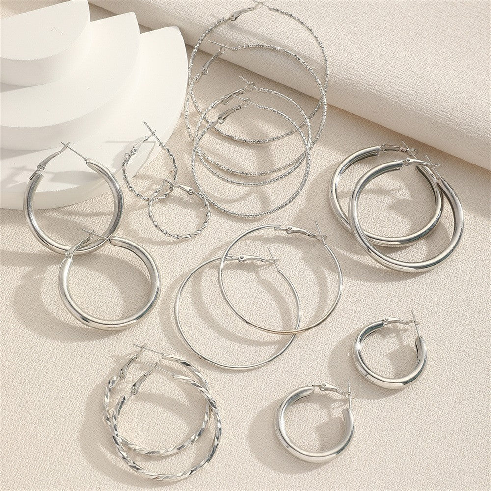 Set of silver hoop earrings on a light fabric background