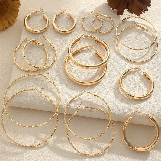 Collection of gold hoop earrings on a textured surface with a floral background.